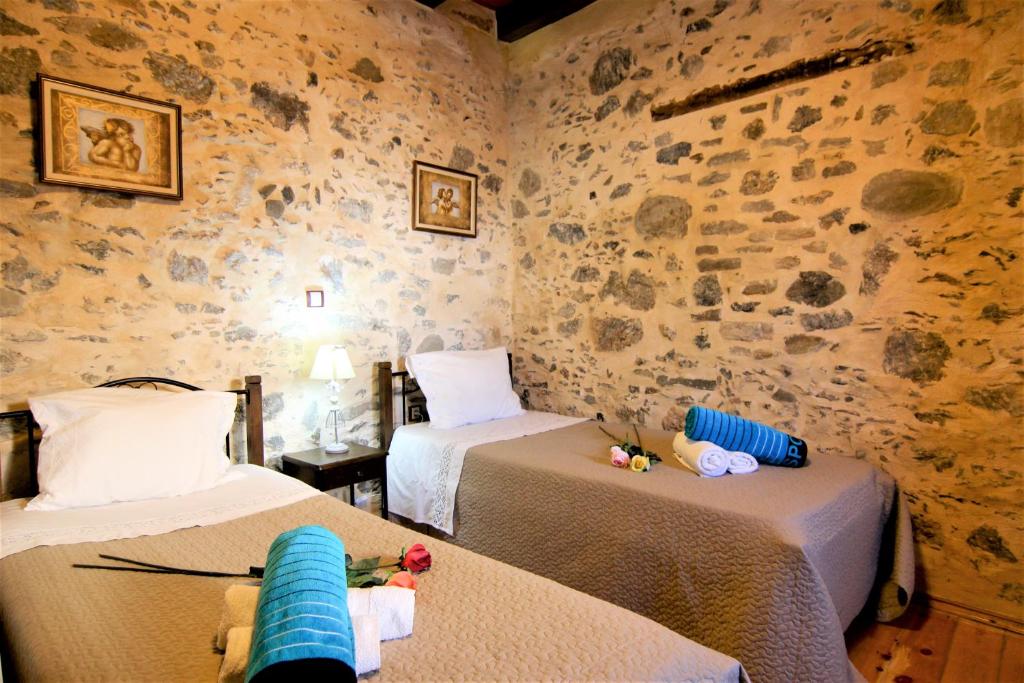 Habitación con 2 camas y pared de piedra. en Afroditi Traditional Villa, en Yiannioú