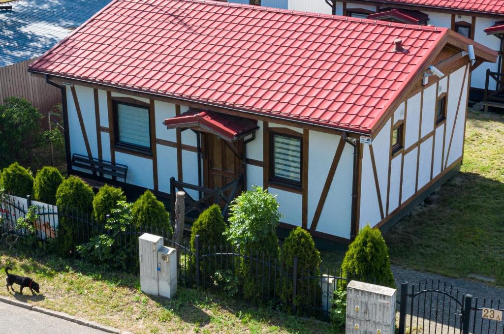 a house with a red roof and a cat walking in front of it at Pustkowo Domki Wakacyjne u Marka in Pustkowo