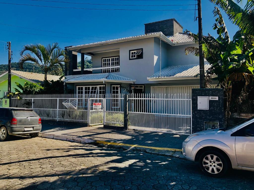 una casa blanca con una valla delante en Residencia da Kel, en Bombinhas