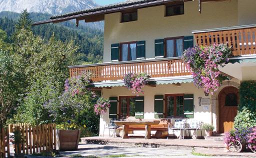 een groot huis met een tafel en stoelen ervoor bij Haus Hirschpoint Ferienwohnungen in Ramsau