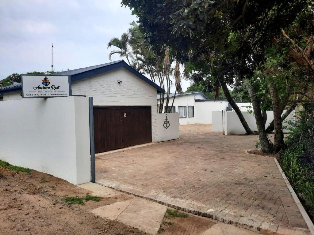 a white building with a gate and a garage at Anchors Rest in Port Shepstone