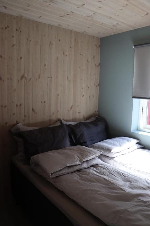 a bed in a room with a wooden wall at Visit Mortsund, Lofoten in Leknes