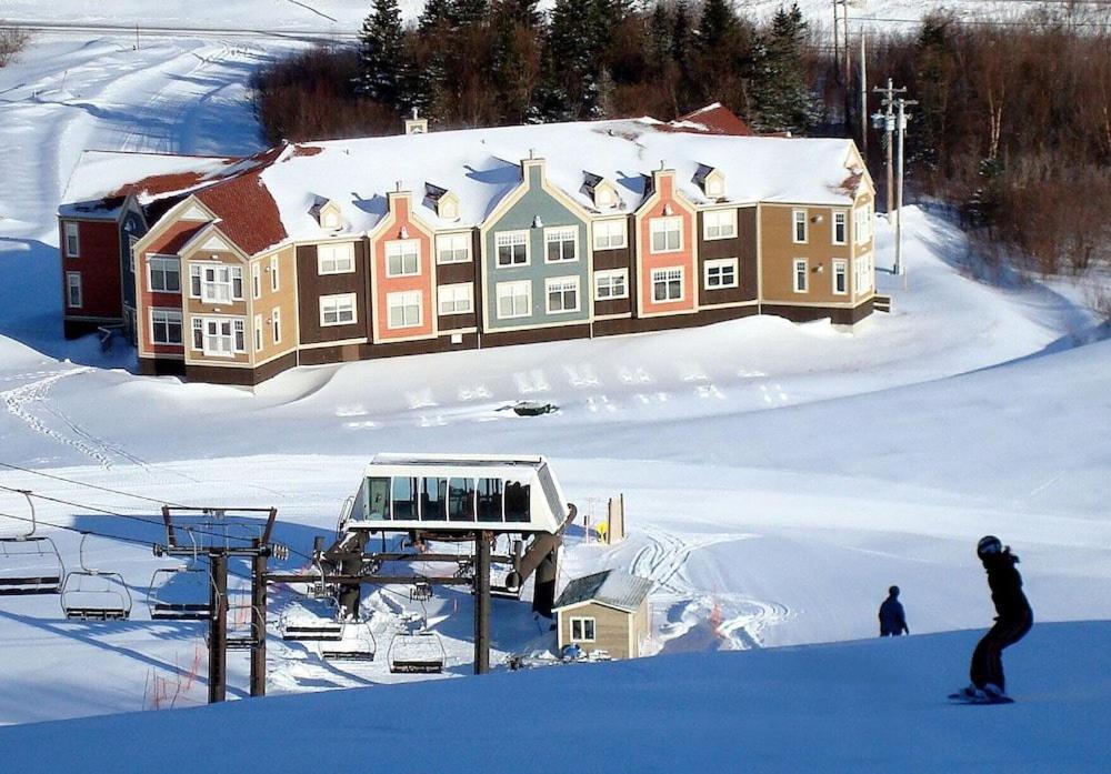 a person riding a snowboard in the snow next to a house at Marble Villa in Steady Brook