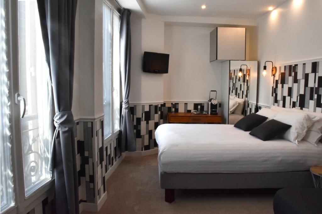 sypialnia z łóżkiem i dużym oknem w obiekcie Hôtel Tilde w Paryżu