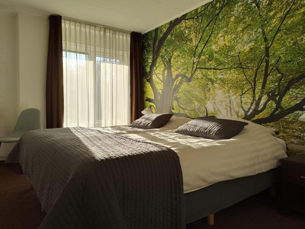 ein Schlafzimmer mit einem Bett mit einem Baumbild an der Wand in der Unterkunft Boutique Hotel de Rozenhof in Heilig Landstichting