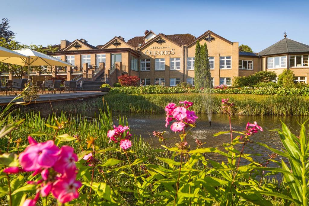 a hotel with pink flowers in front of a pond at Romantik Hotel Waldschlösschen in Schleswig