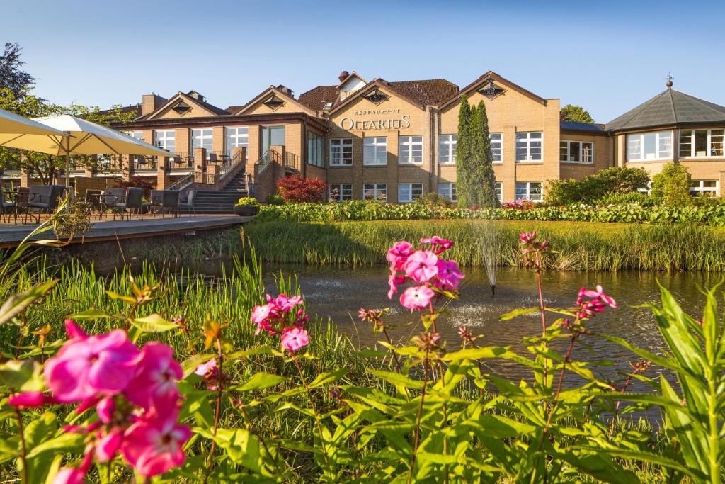 un hôtel avec des fleurs roses en face d'un étang dans l'établissement Romantik Hotel Waldschlösschen, à Schleswig