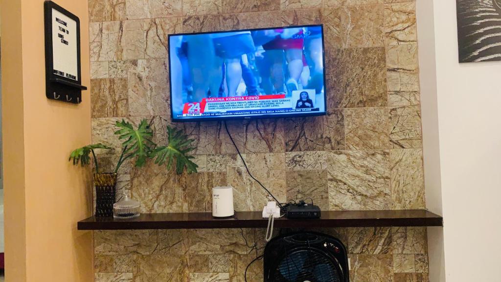 a tv on a stone wall in a room at Son's Condo SMDC Wind Tagaytay in Tagaytay