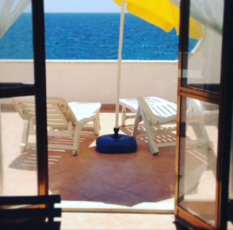 un balcone con due sedie e un ombrellone su una nave di Villa Nicole - NP a Punta Prosciutto