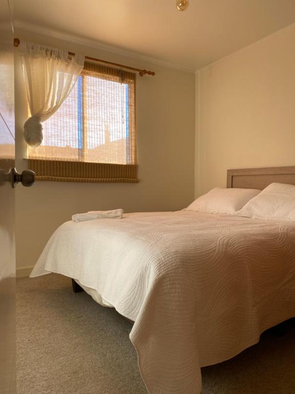 een slaapkamer met een wit bed en een raam bij Casa Patagonia #1015 in Coihaique