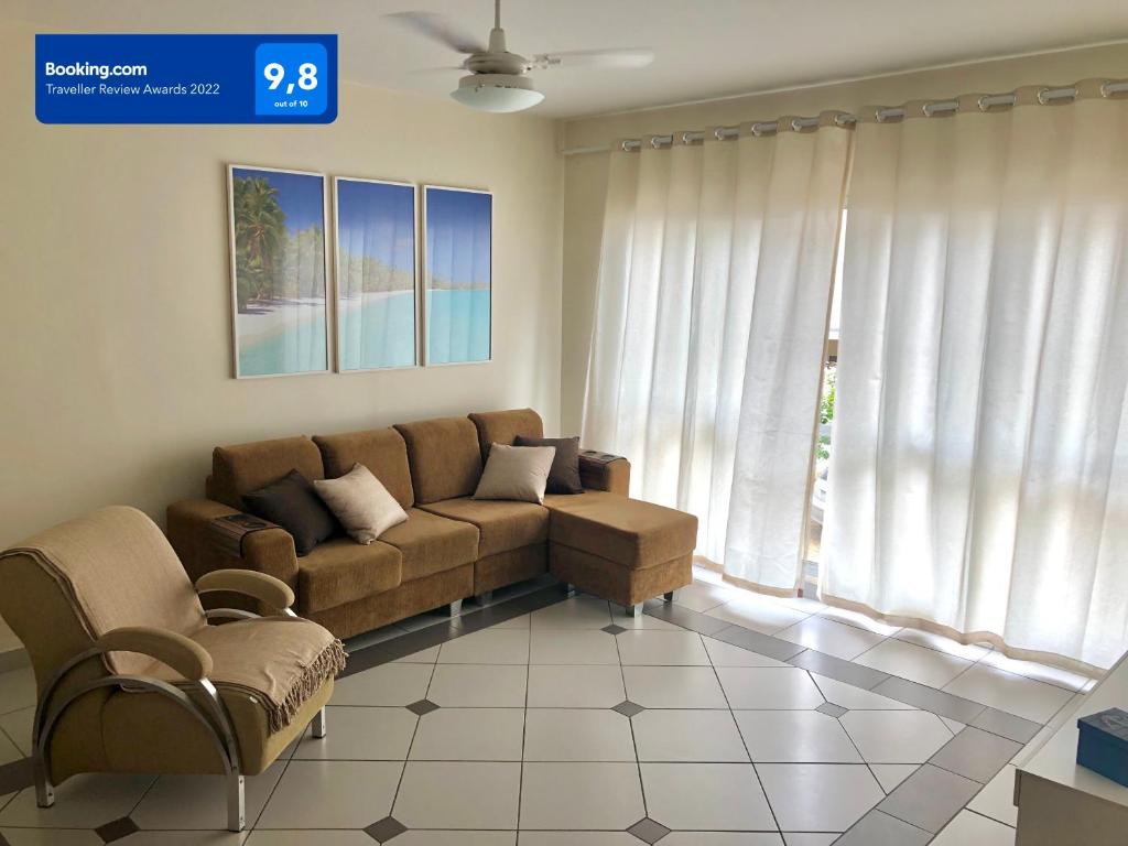 uma sala de estar com um sofá e uma janela em Apartamento Enseada Guarujá - 350m do Mar! no Guarujá