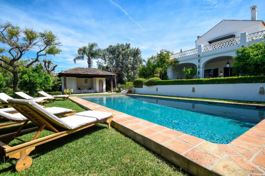 マルベーリャにあるSpacious Andalusian-inspired Villa with Scenic Viewsのラウンジチェア付きのスイミングプール、家