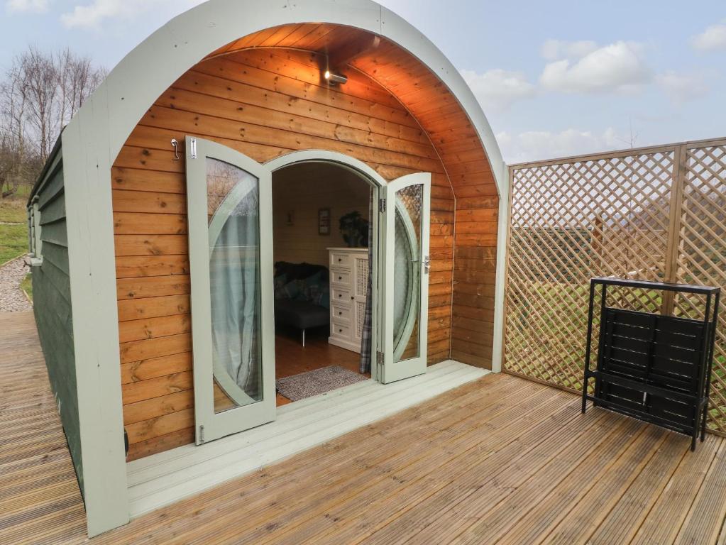 una pequeña casa de madera con un arco en una terraza en Hare en Keighley