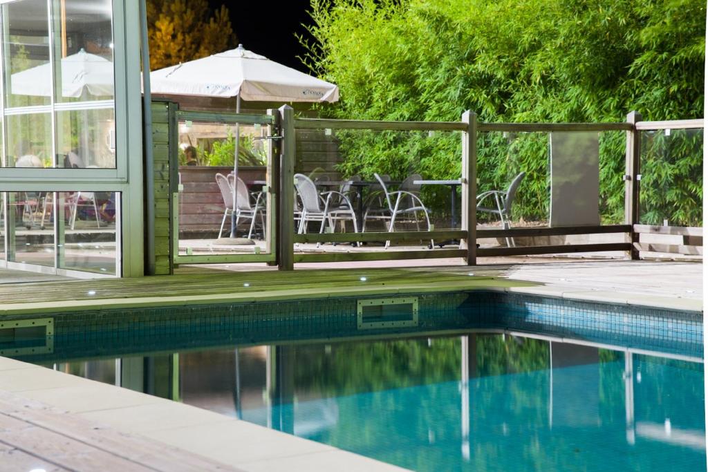 a pool with chairs and an umbrella next to a table at Best Western Hotel Le Bordeaux Sud in Gradignan