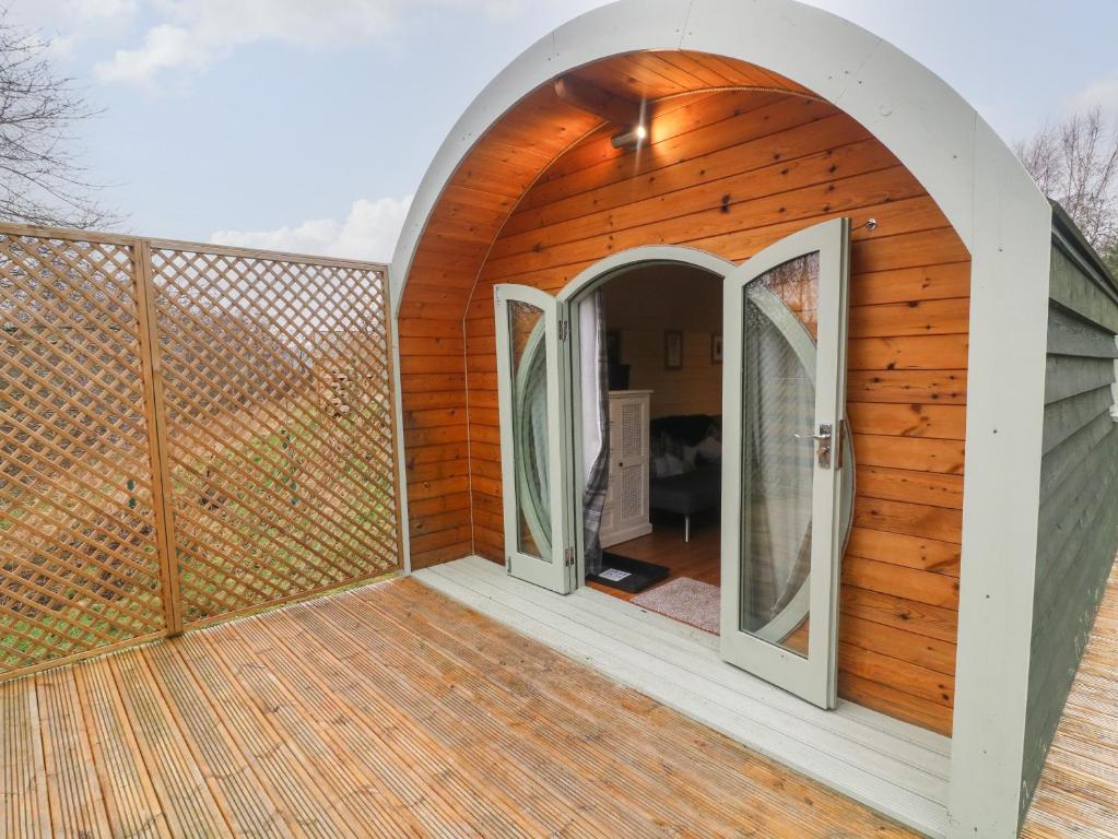a wooden house with an arched door on a deck at Otter in Keighley