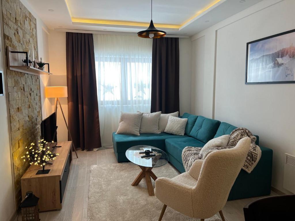 ein Wohnzimmer mit einem blauen Sofa und einem Tisch in der Unterkunft Milmari Apartman Haski N55 in Kopaonik