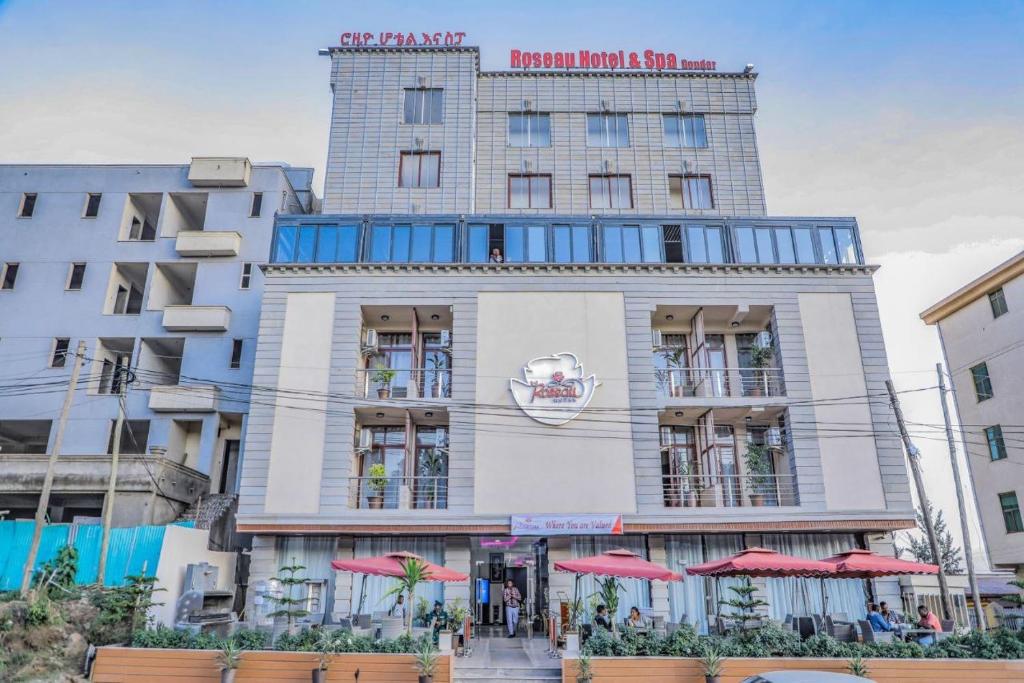 un edificio alto con sombrillas rojas delante en Roseau Hotel And Spa, en Gondar