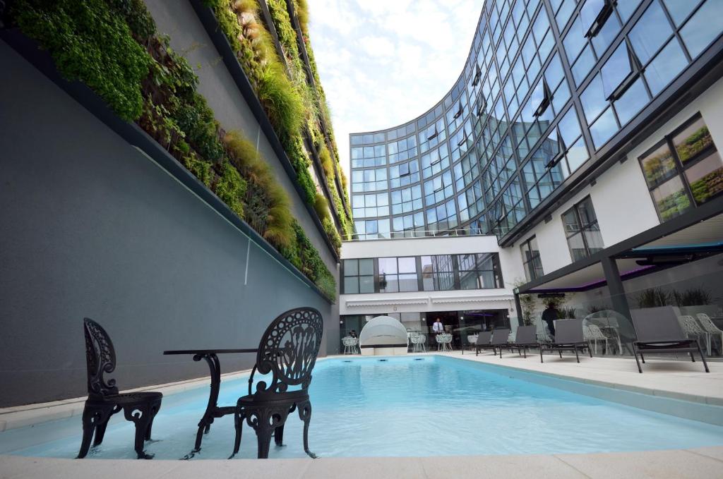 a pool with two chairs and a table in a building at Holiday Inn Dijon Toison D'or by IHG in Dijon