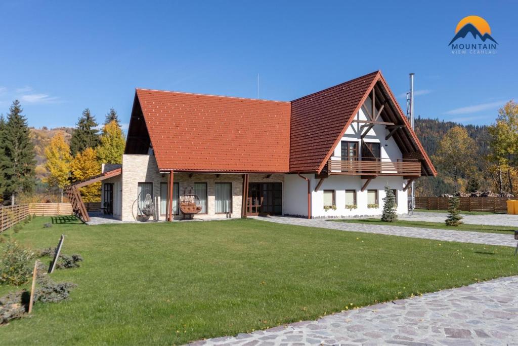 une maison avec une grande pelouse devant elle dans l'établissement Mountain View Ceahlau, à Ceahlău