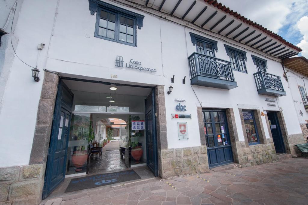 un edificio bianco con porte e finestre nere di Hotel Limacpampa a Cuzco