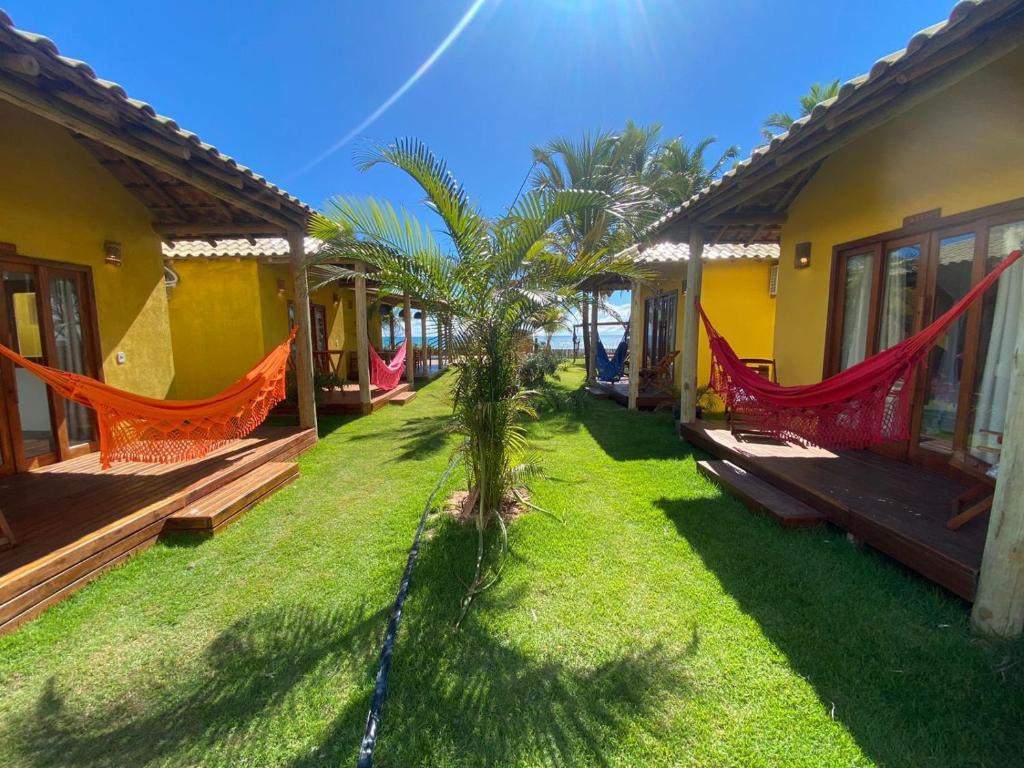 einen Hof mit Hängematten und ein Haus mit Gras in der Unterkunft Villa do Sossego - Caraíva in Caraíva