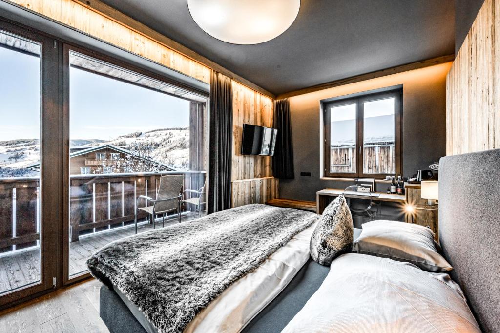 sypialnia z łóżkiem i dużym oknem w obiekcie ALMMONTE SENSUM SUITES Boutique Hotel w mieście Wagrain
