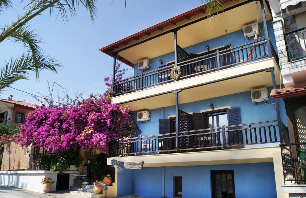 um edifício azul com uma varanda e uma árvore com flores roxas em Dominici em Ammouliani