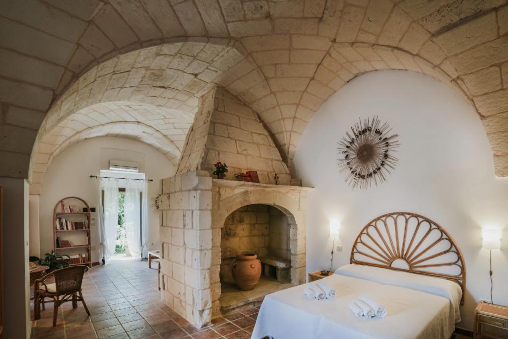 a bedroom with a stone fireplace and a bed at Agriturismo Masseria del Bosco Makyva in Borgagne