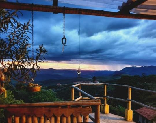 a balcony with a bench and a view of the mountains at Pousada Pouso e Prosa in Lavras Novas