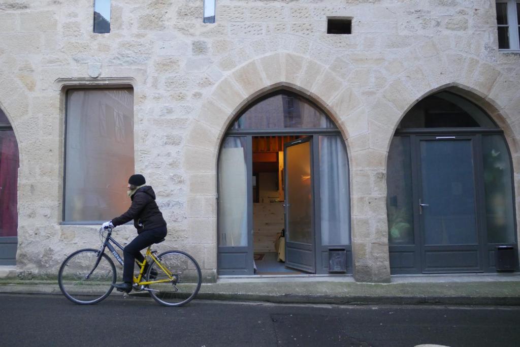 un hombre montando una bicicleta delante de un edificio en Consulat Figeac, en Figeac