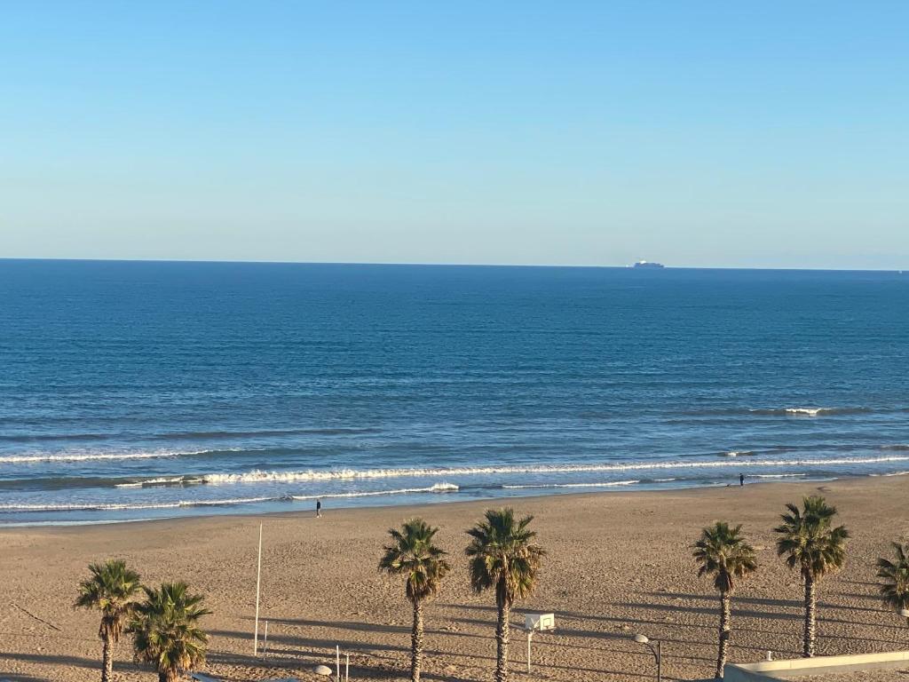 a beach with palm trees in front of the ocean at Avenida Mare Nostrum 7 Patacona Beach Includes breakfast in Valencia