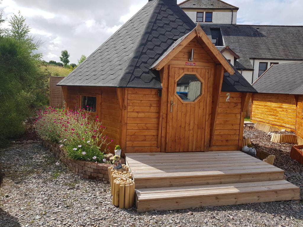 um pequeno chalé de madeira com um deque de madeira em Unique luxury cabin 2 em Inverness