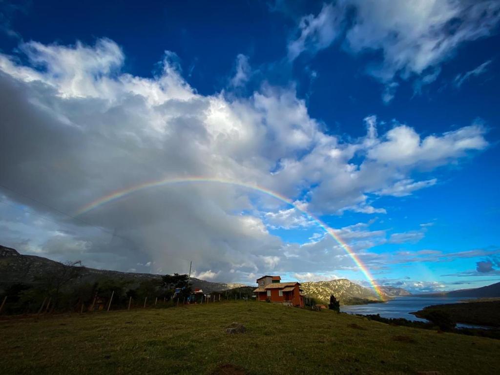 un arco iris en el cielo sobre un campo en Chalé Paz Central do Paraíso Lapinha da Serra, en Santana do Riacho