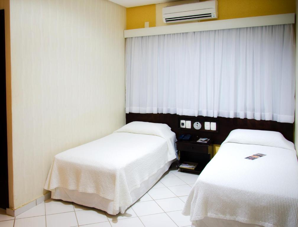 a hotel room with two beds and a window at Pousada dos Girassóis in Palmas
