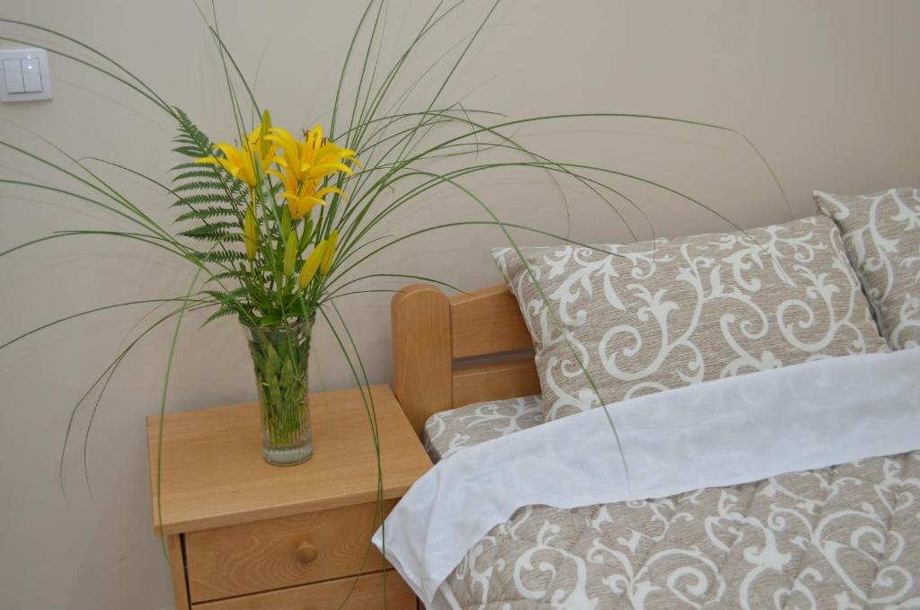 un vaso di fiori gialli su un tavolo accanto a un letto di Guest House Konak Iris a Predejane