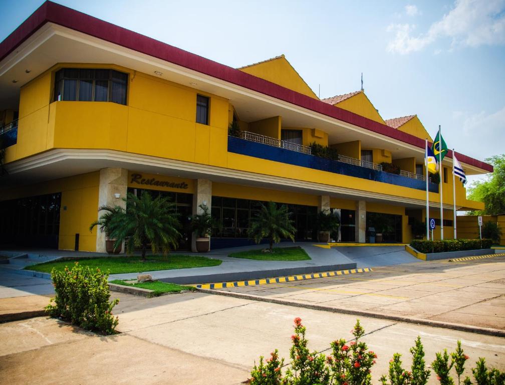 un gran edificio amarillo con una bandera delante de él en Pousada dos Girassóis en Palmas