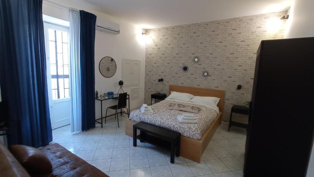 sypialnia z łóżkiem i ceglaną ścianą w obiekcie Casa Barocco Catania w Katanii
