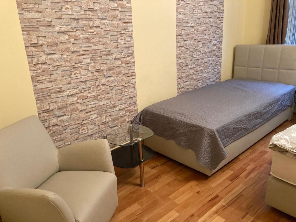 a bedroom with a bed and a chair and a brick wall at Szent János Vendégház in Eger
