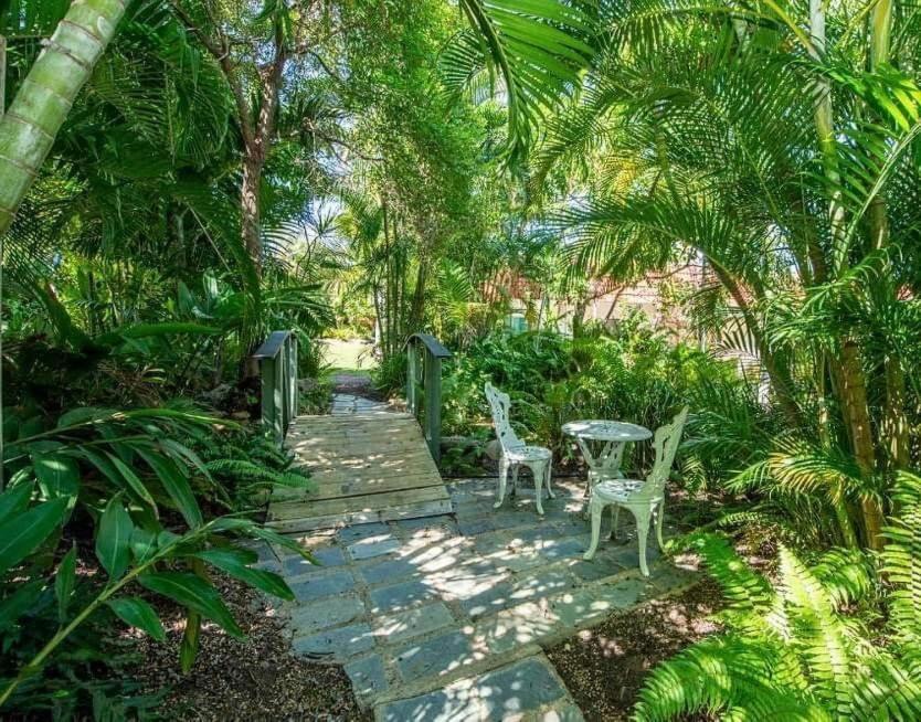 a wooden pathway with two chairs and a table in a garden at Harmony Haven in Nelly Bay