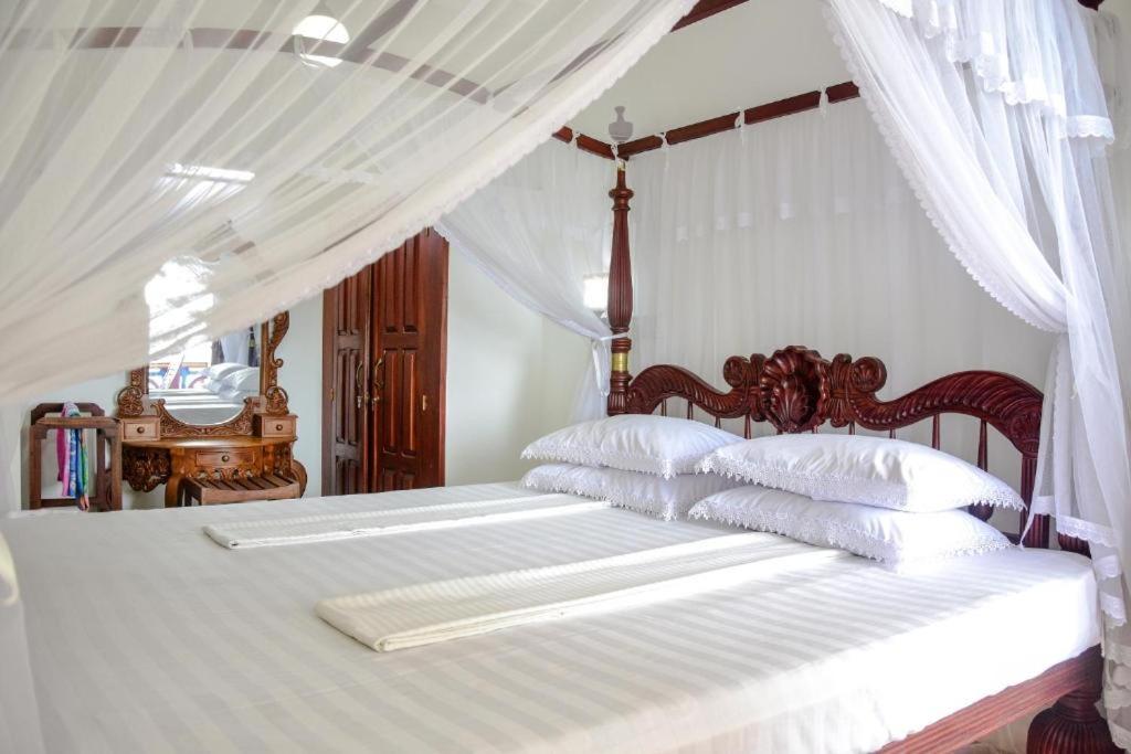 a bedroom with two beds with white sheets and pillows at Hotel Dolphin Hikkaduwa in Hikkaduwa