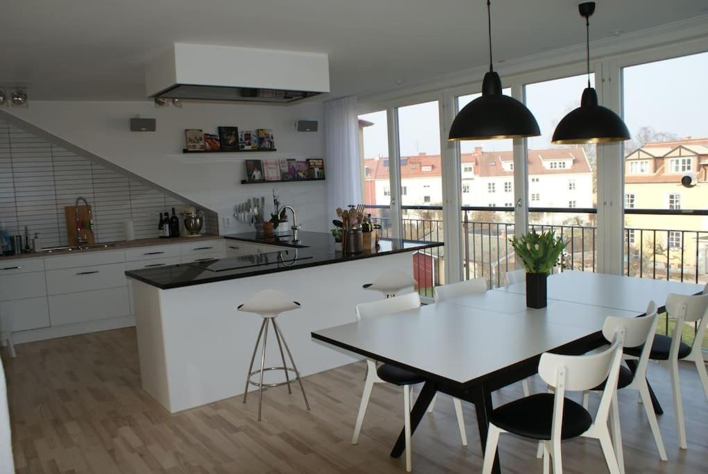 Lyxig vindsvåning nära Kalmar slott och havet في كالمار: مطبخ مع طاولة وكراسي ومطبخ مع نوافذ