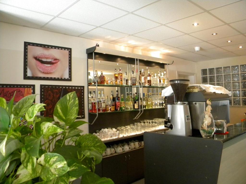 un bar con un estante lleno de botellas y vasos en Hotel Ariston Imperial, en Porto Garibaldi