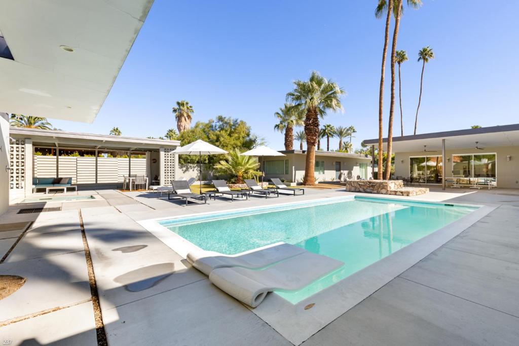 een zwembad met ligstoelen en een huis bij Modern Palms in Palm Springs