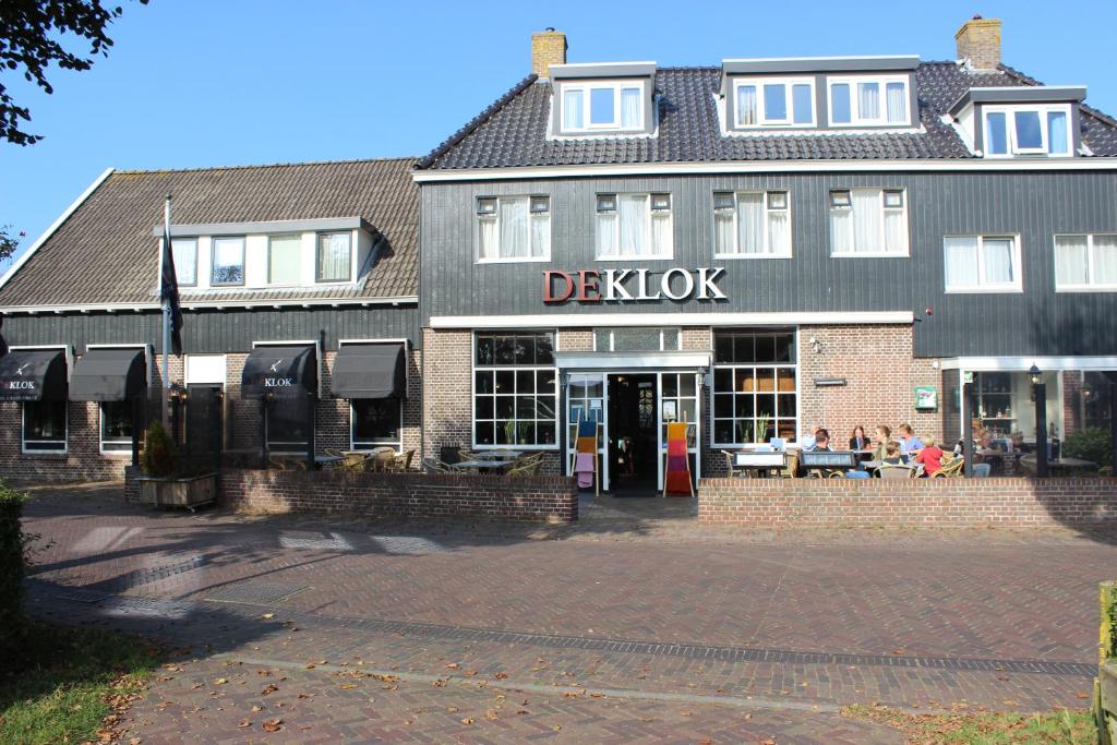 Hotel "De Klok" في بورين: مبنى adenk مع أشخاص يجلسون خارجه