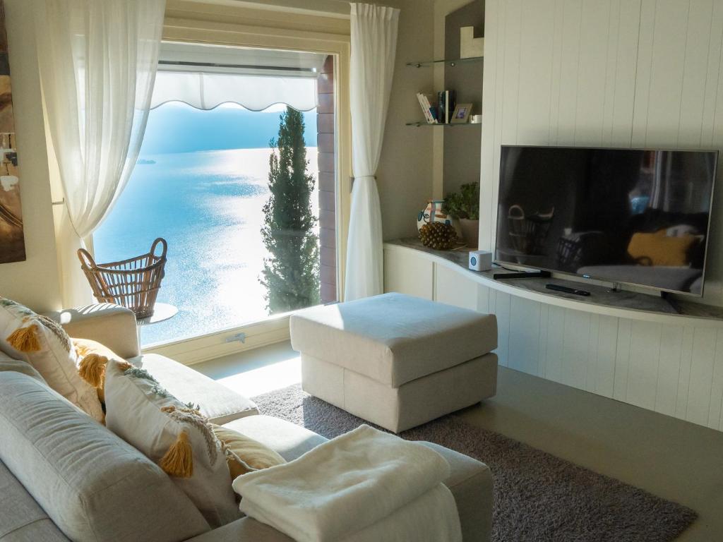 a living room with a couch and a large window at Colosseo with wonderful lake view and swimming pool in Parzanica