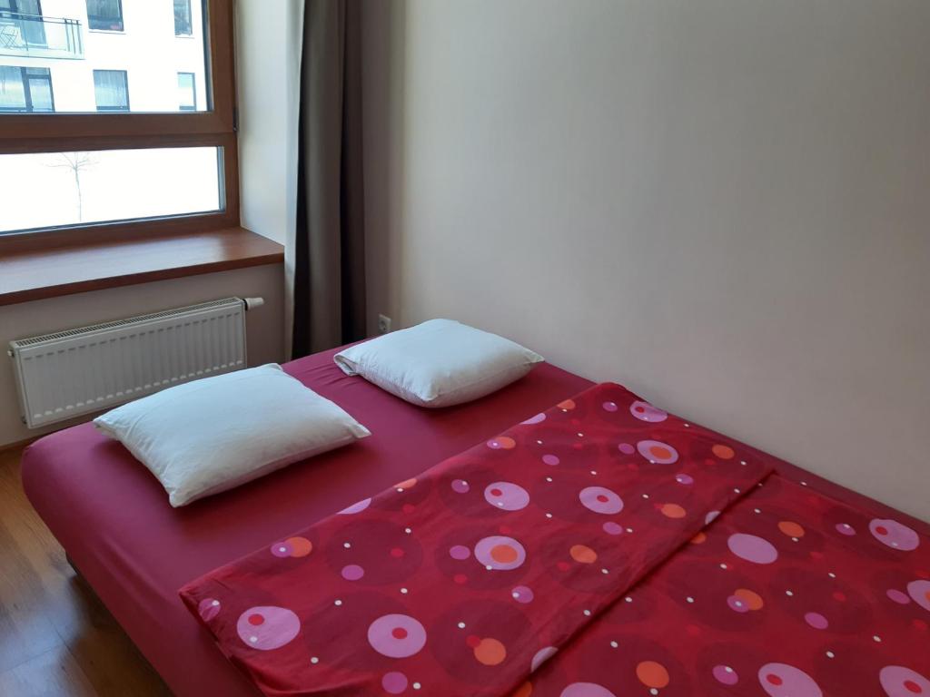 a red bed with two pillows on it next to a window at Žvėryno appartment-Self check-in-Free garage in Vilnius