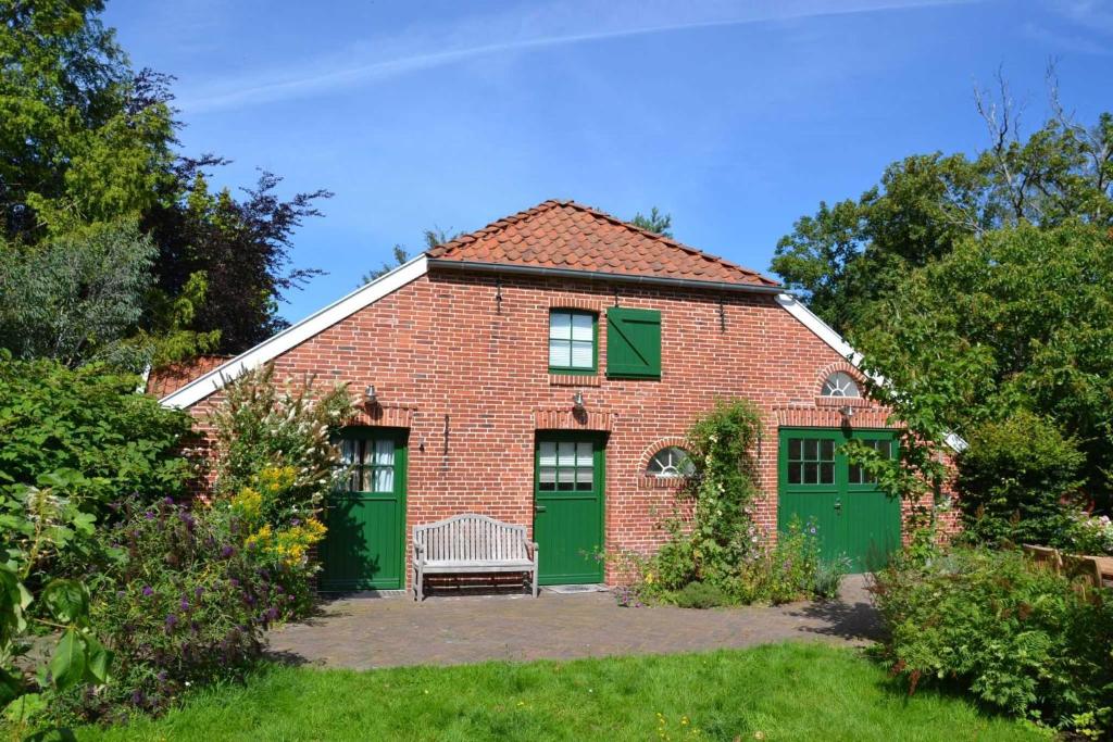 a brick house with green doors and a bench at Doppelzimmer Holthusen 25515 in Weener
