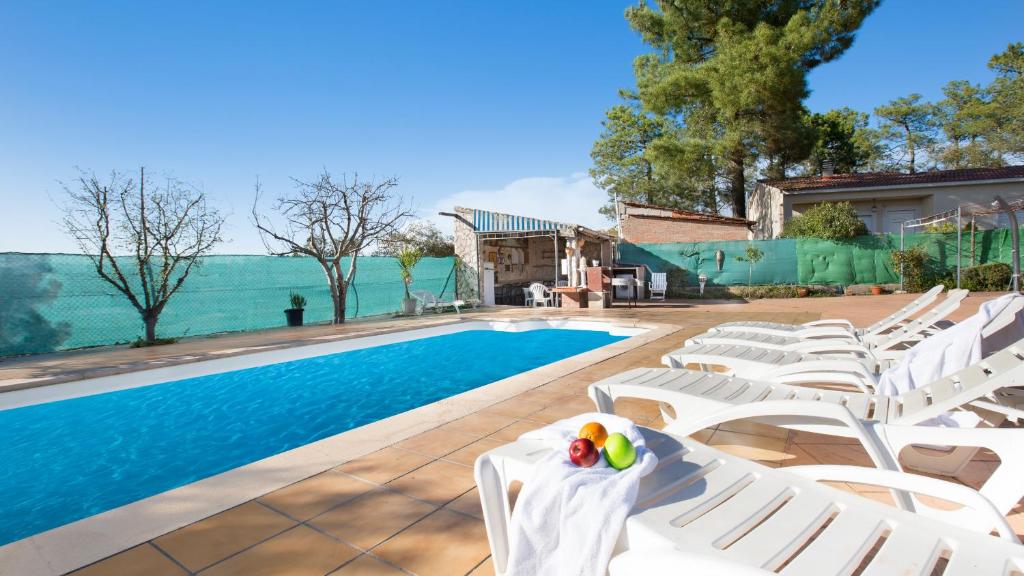 uma piscina com espreguiçadeiras brancas e uma piscina em 2Alo - Lloret de Mar em Mont Barbat