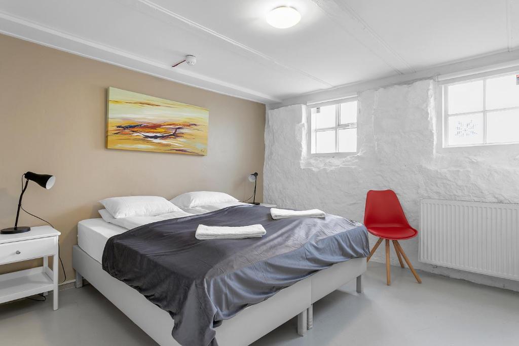 um quarto com uma cama e uma cadeira vermelha em Berg Apartments em Reykjavík