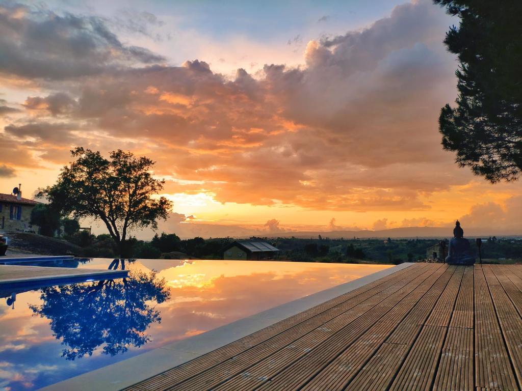 a swimming pool with a sunset in the background at Quinta dos Corgos in Tábua
